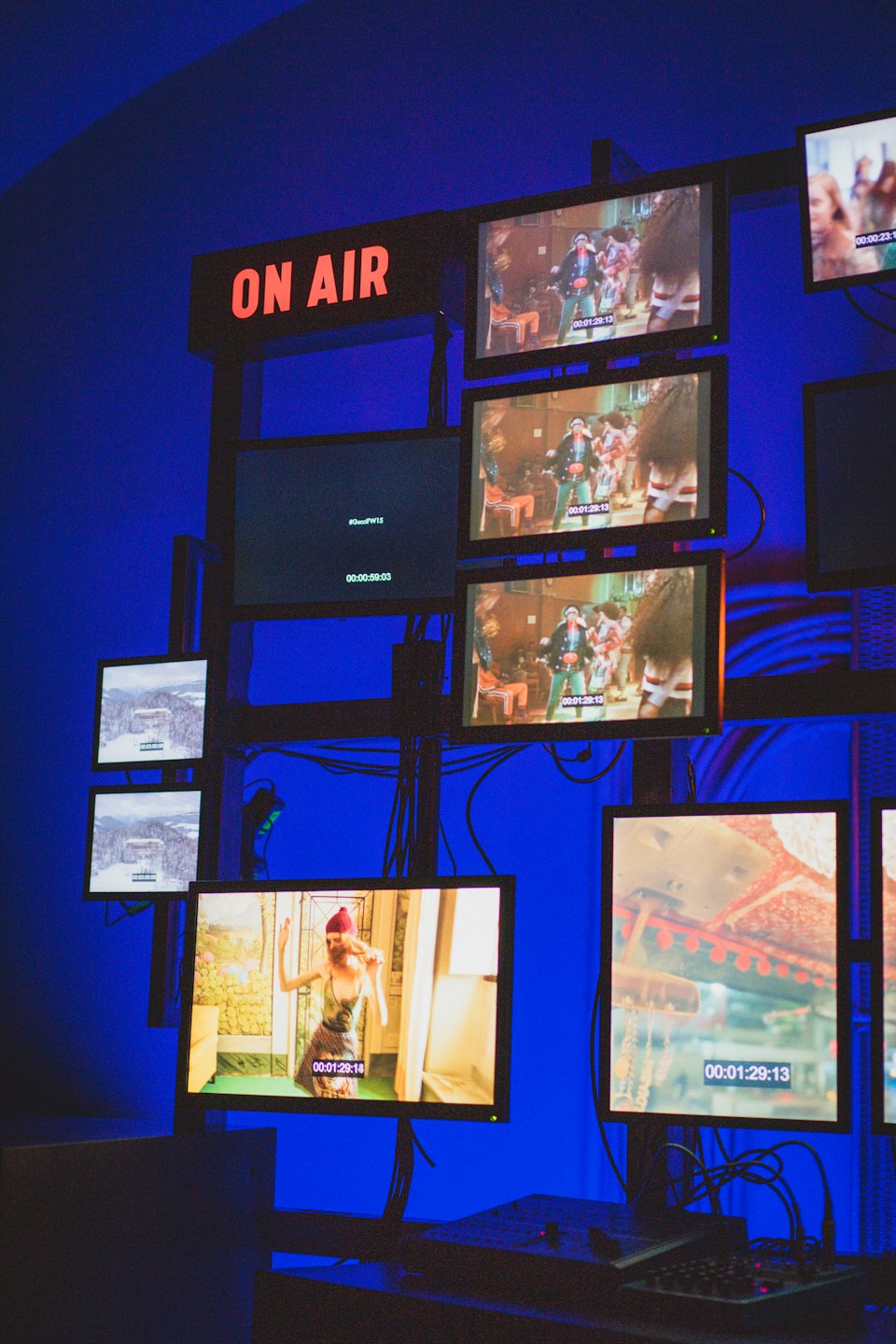 Video control room with screens showing live feeds and an on-air sign.